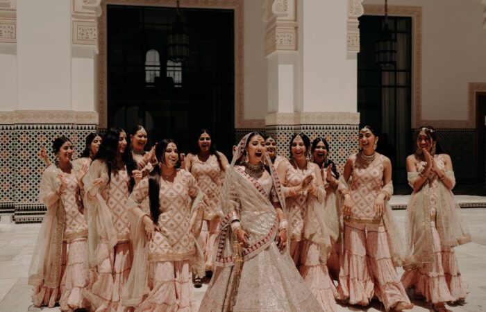 Sikh bride making a happy, surprised expression while surrounded by female friends and family.